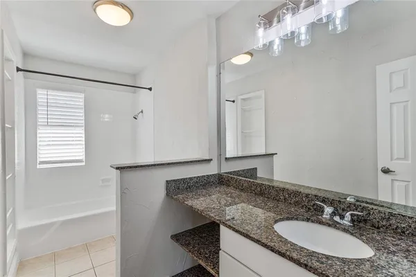a bathroom with a granite countertop sink a mirror and a bathtub