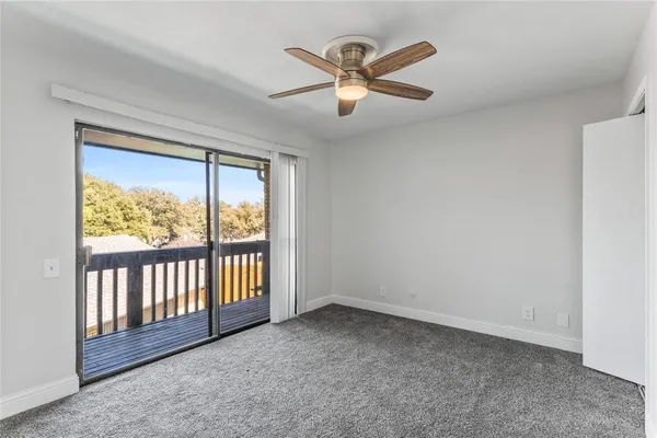an empty room with ceiling fan and window