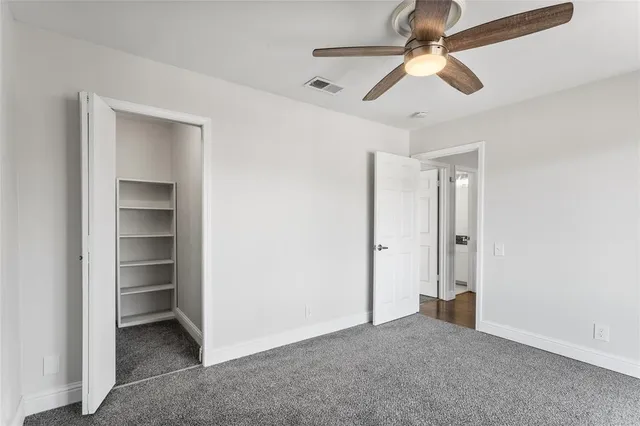 an empty room with closet and a ceiling fan