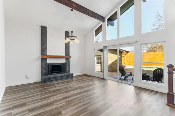 an empty room with wooden floor fireplace and windows