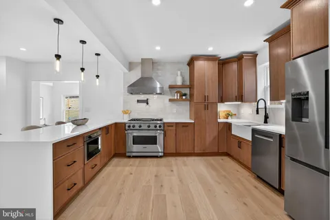 a large kitchen with stainless steel appliances sink a stove and cabinets