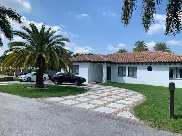 a view of a house with a yard and palm trees