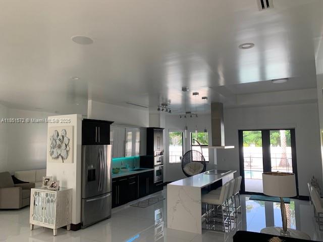 19260 Southwest 134th Ave Road Miami, FL 33177 - Photo 4 of 14 a kitchen with stainless steel appliances kitchen island granite countertop a refrigerator a sink dishwasher a dining table and chairs with wooden floor