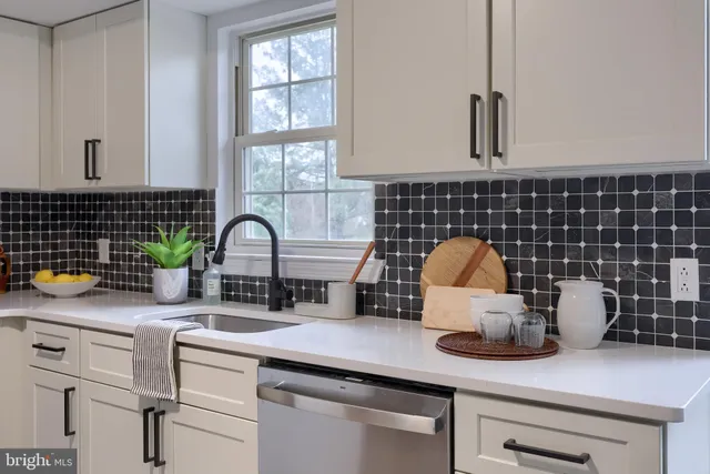 a kitchen with a sink white cabinets and appliances