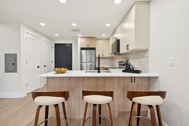 a kitchen with stainless steel appliances a dining table chairs refrigerator and sink