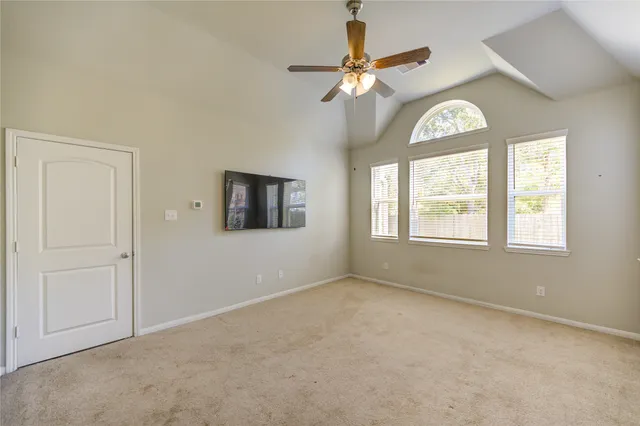 an empty room with chandelier fan and windows
