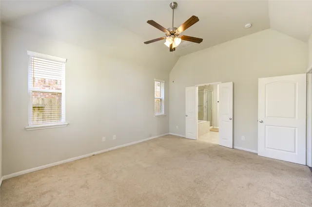 an empty room with a chandelier fan and windows