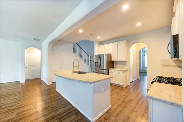a large room with kitchen island a sink wooden floor and a large window