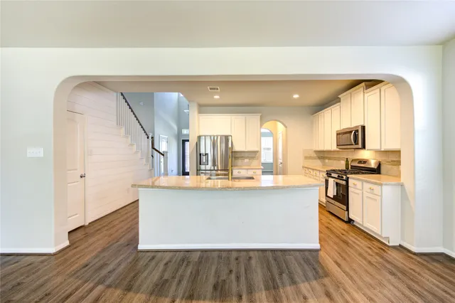 a view with kitchen island wooden floors stainless steel appliances and window