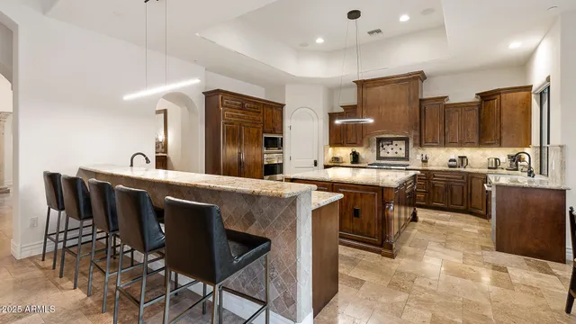 a kitchen island with stainless steel appliances kitchen island granite countertop a table chairs sink and cabinets