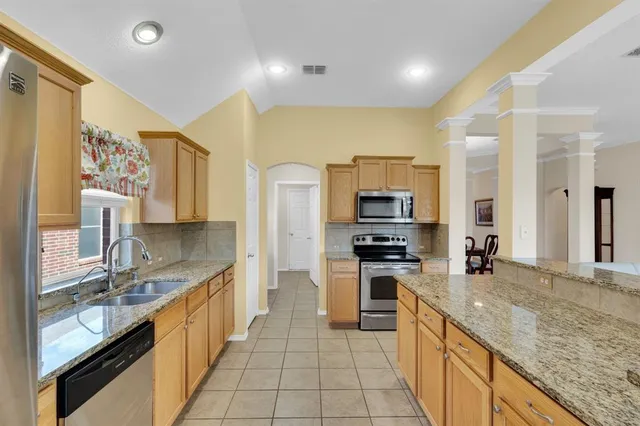 a kitchen with granite countertop a sink a counter top space and stainless steel appliances