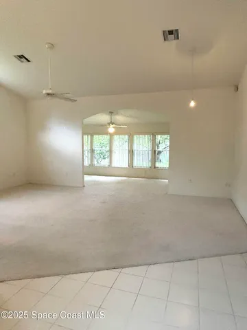 an empty room with windows and chandelier fan
