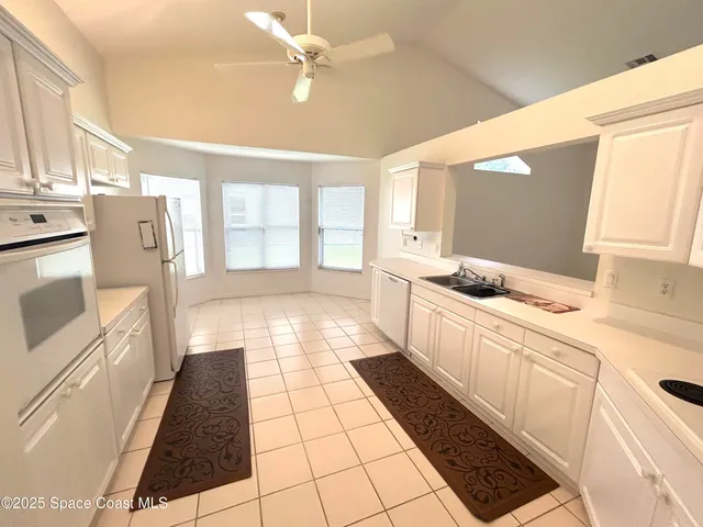 a kitchen with a sink a stove top oven and white cabinets