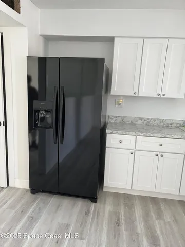 a kitchen with a refrigerator and white cabinets
