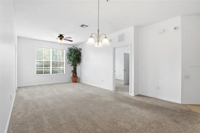 an empty room with windows and ceiling fan