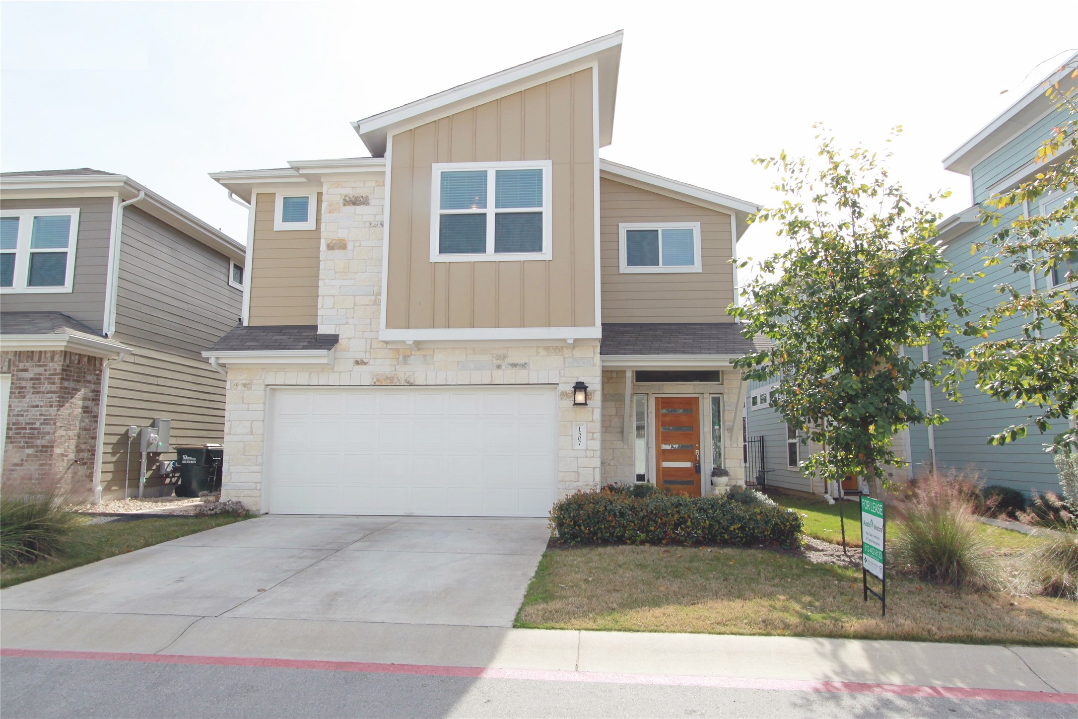 Modern exterior featuring stone veneer, vertical siding, and a two-car garage