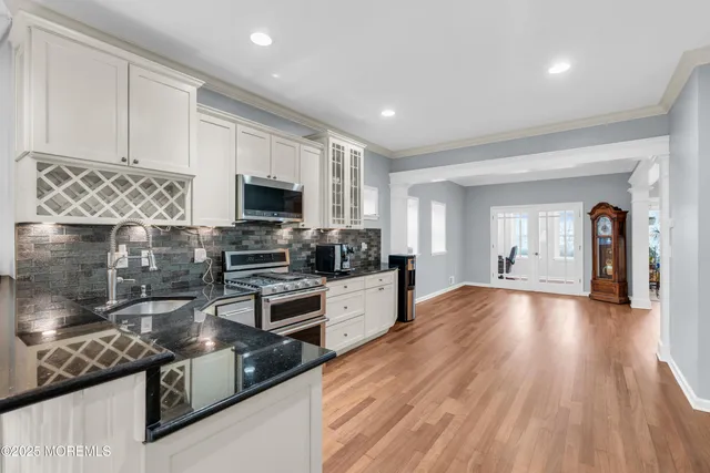 a large kitchen with stainless steel appliances granite countertop a stove and a wooden floors
