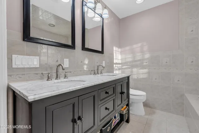 a bathroom with a granite countertop toilet sink and mirror