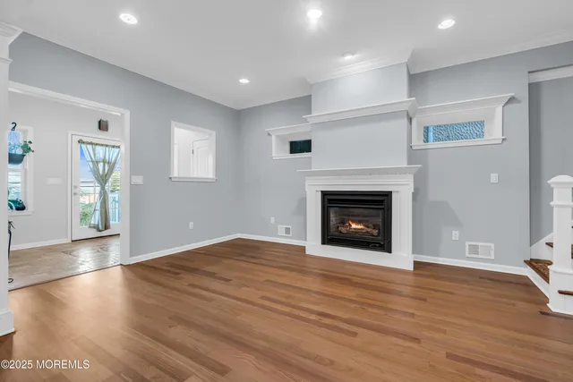 a view of an empty room with wooden floor fireplace and a window