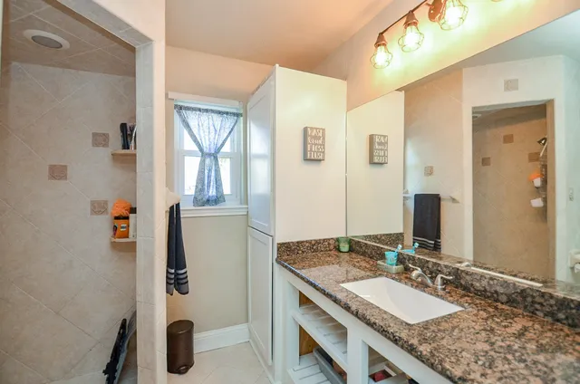 a bathroom with a granite countertop sink and a mirror