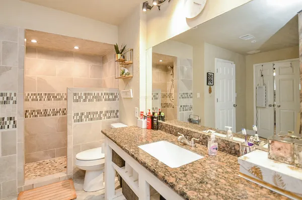 a bathroom with a granite countertop sink mirror vanity and toilet