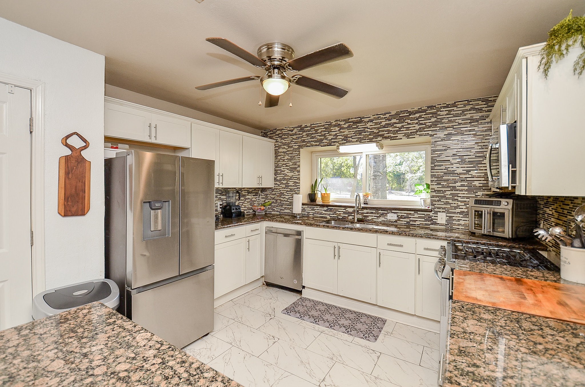 720 Surrey Drive Simonton, TX 77485 - Photo 7 of 34 a kitchen with stainless steel appliances granite countertop a refrigerator a sink and white cabinets