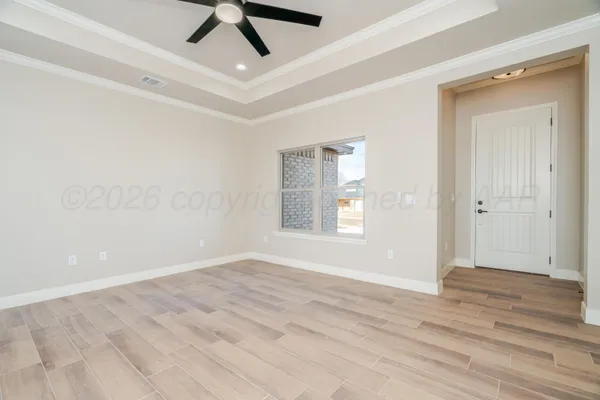 an empty room with wooden floor fan and windows
