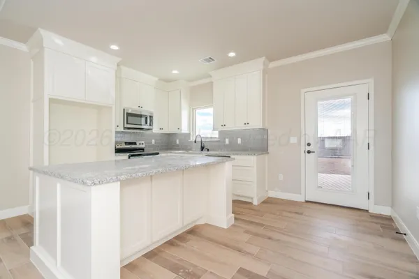 a kitchen with kitchen island granite countertop a sink and cabinets