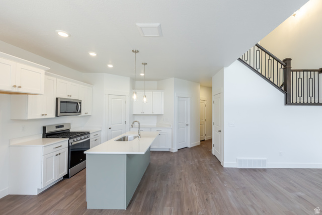 4816 Heartwood Road, Unit 423 Mapleton, UT 84664 - Photo 10 of 21 Kitchen featuring stainless steel appliances, white cabinets, a kitchen island with sink, and dark wood finished floors