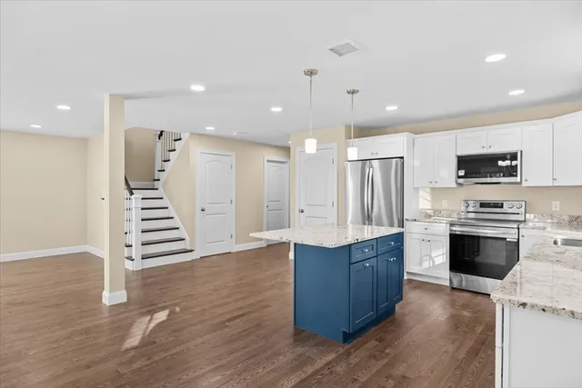 a kitchen with kitchen island white cabinets and stainless steel appliances