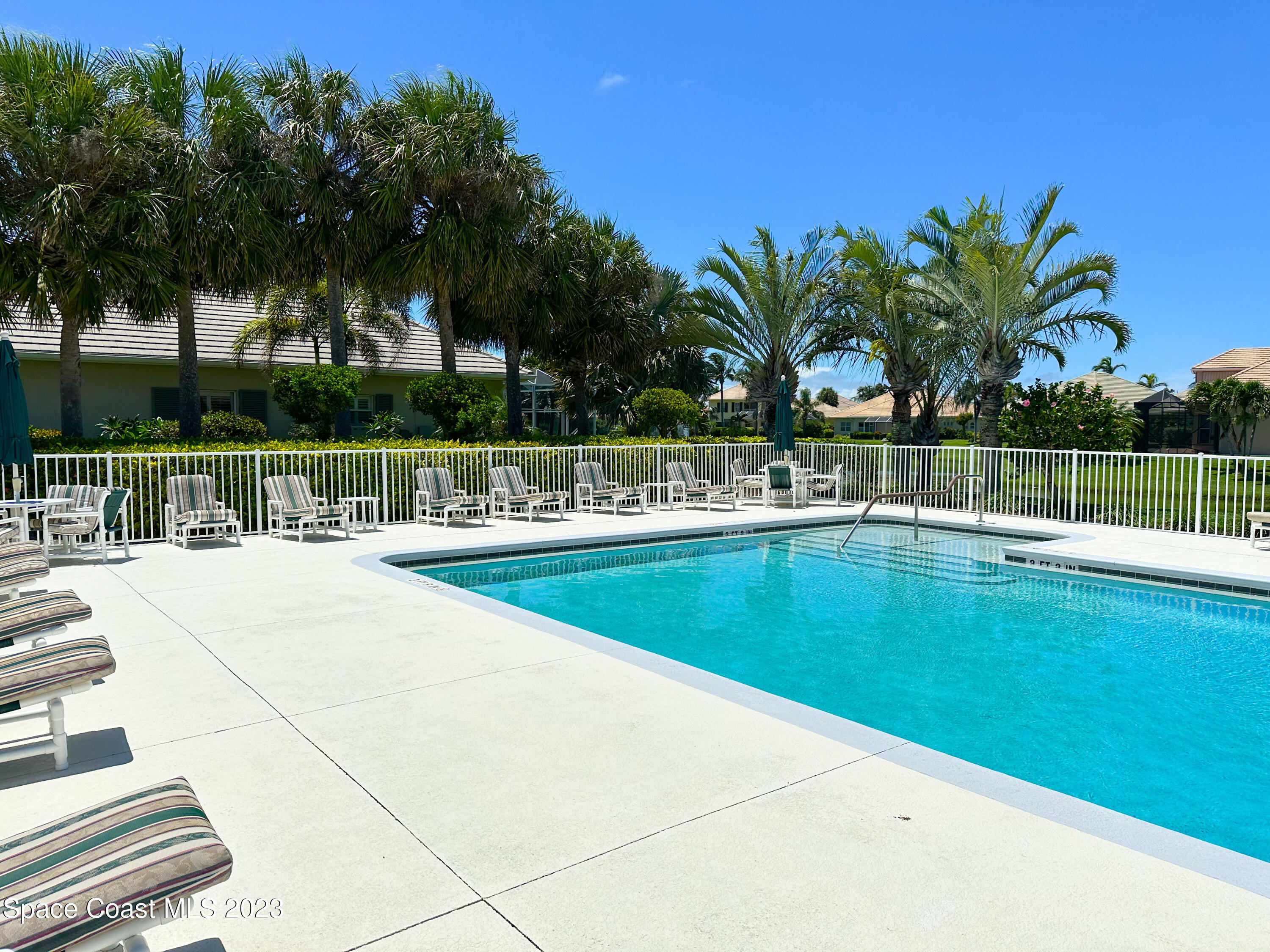 245 Clyde Street Melbourne Beach, FL 32951 - Photo 77 of 88 a view of a swimming pool with a lounge chair and palm trees