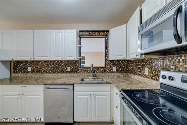 a kitchen with granite countertop a sink stove and cabinets