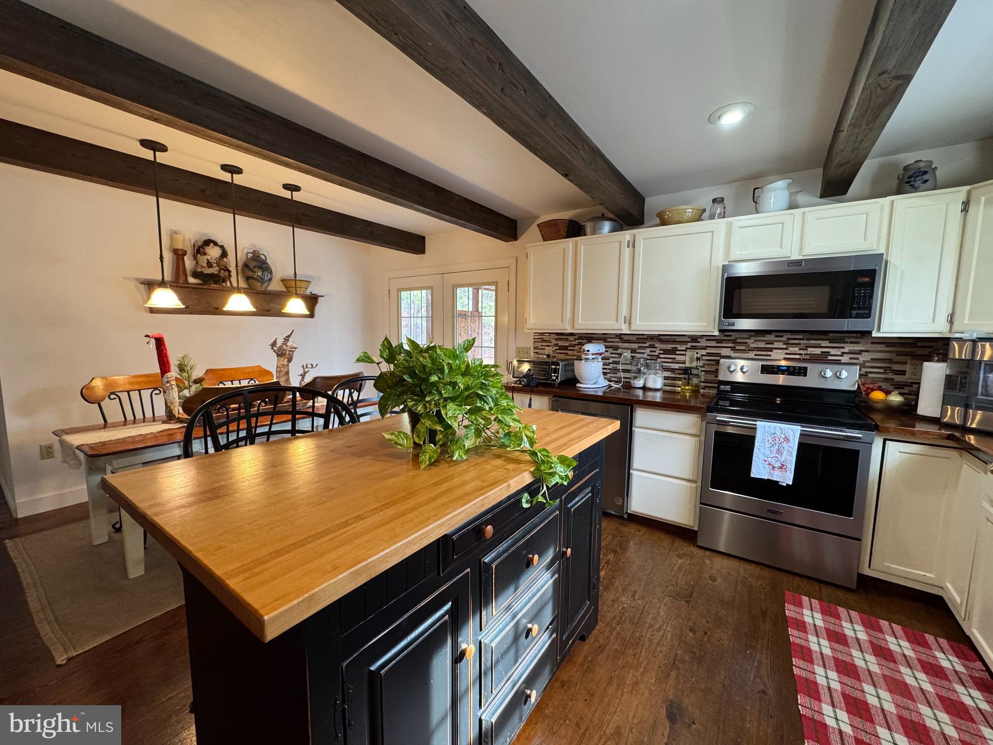 26759 Old State Road Crisfield, MD 21817 - Photo 7 of 17 a kitchen with stainless steel appliances granite countertop a stove a sink dishwasher a microwave oven and a dining table with wooden cabinet