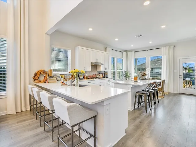 a kitchen with a dining table chairs wooden floor appliances and cabinets