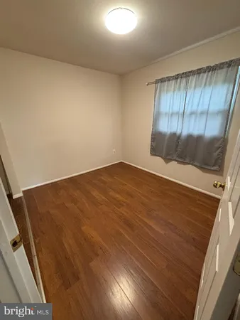 an empty room with wooden floor and fan