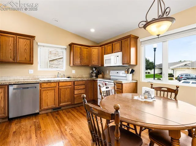 a kitchen with granite countertop a stove a sink a dining table and chairs