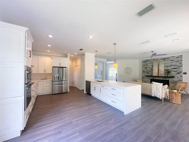 a kitchen with stainless steel appliances kitchen island wooden floors stove and white cabinets