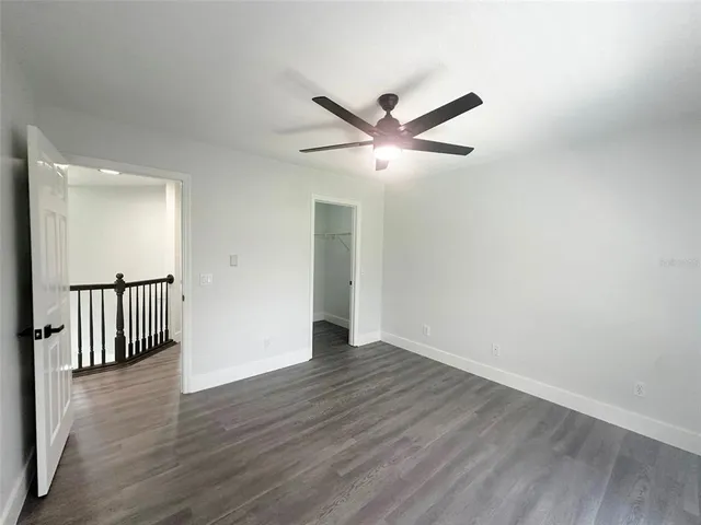 an empty room with wooden floor and a ceiling fan