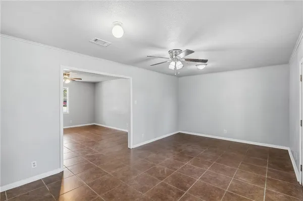 an empty room with white walls and chandelier fan