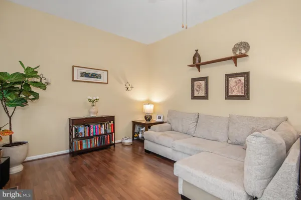 a living room with furniture and a bookshelf with wooden floor