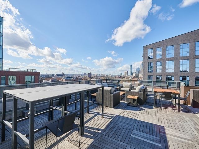 a view of a roof deck with table and chairs couches with wooden floor and fence