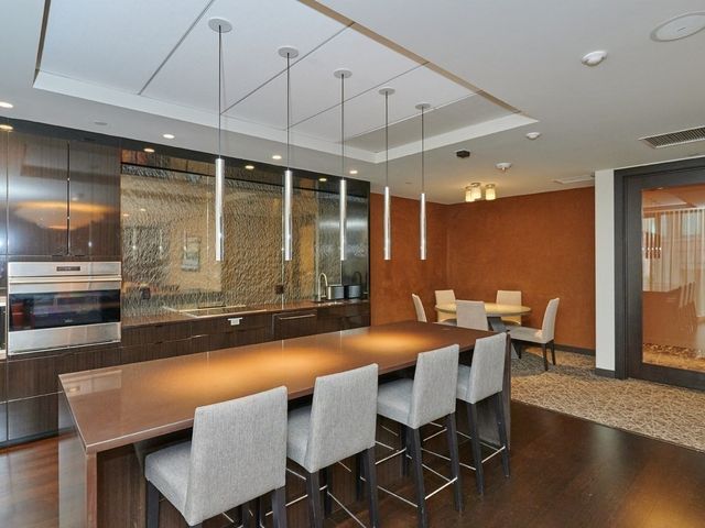 a dining hall with stainless steel appliances a dining table and chairs with wooden floor