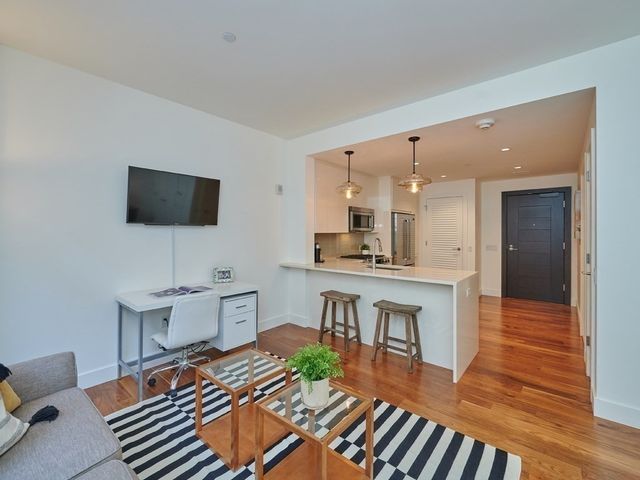 a living room with furniture a flat screen tv and kitchen view