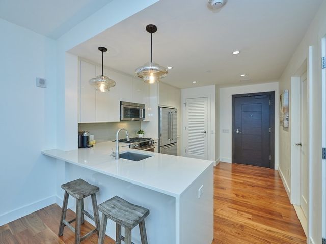 a kitchen with kitchen island stainless steel appliances a dining table chairs sink and cabinets