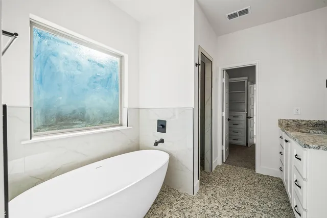 a bathroom with a granite countertop sink a mirror and a bathtub
