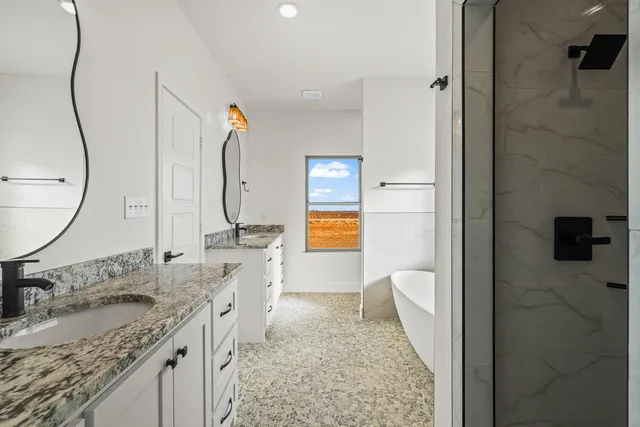 a spacious bathroom with a granite countertop sink a mirror and shower