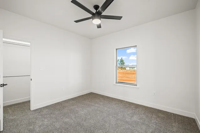 an empty room with a window and a ceiling fan