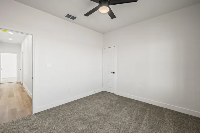 an empty room with a ceiling fan and carpet