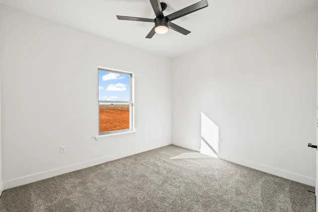 an empty room with a window and a ceiling fan