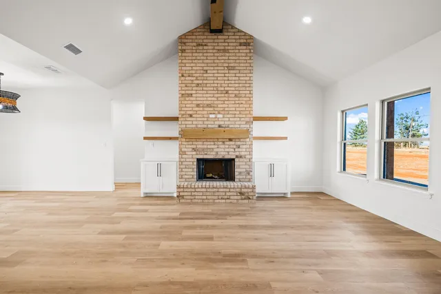 a view of an empty room with a fireplace and a window